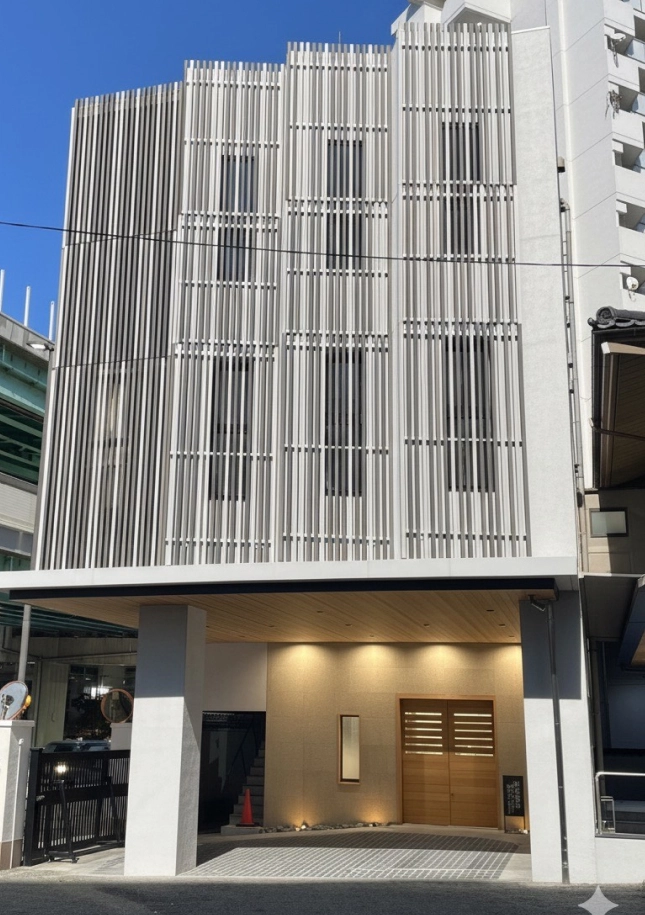 白い壁と木の玄関口が見える、モダンな納骨堂の外観写真